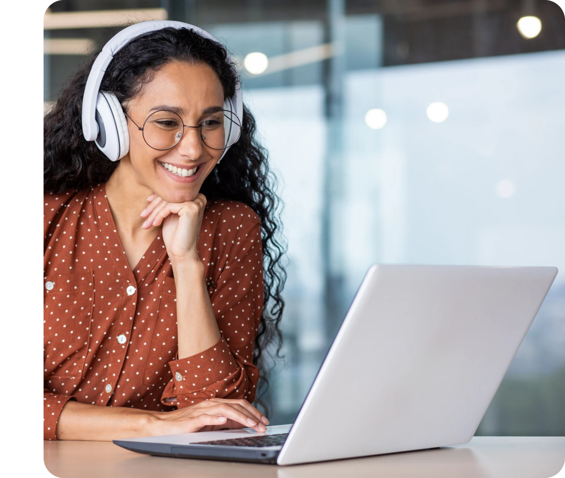 A woman wearing headphones and sitting at a table with her laptop.