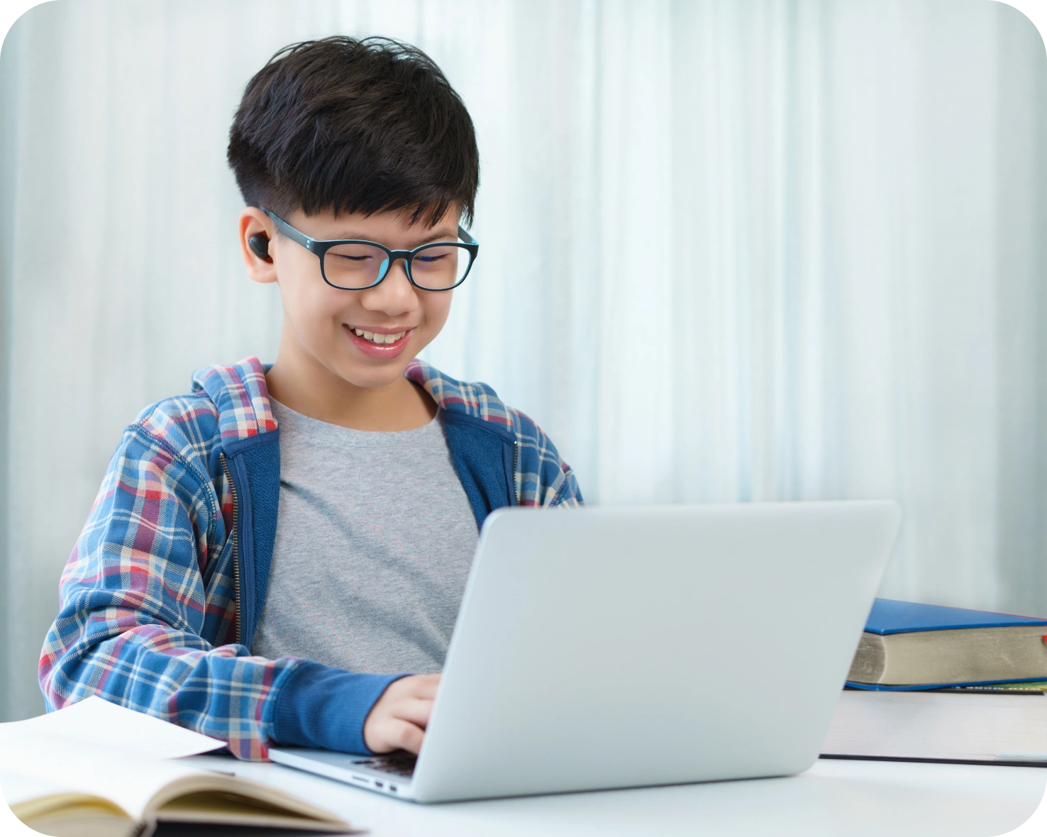 A boy is sitting at his desk on the computer.